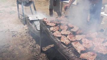 Deux hommes grillant de la viande sur le barbecue video