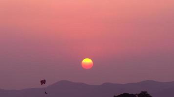 sole rosso che tramonta e parapendio a motore video