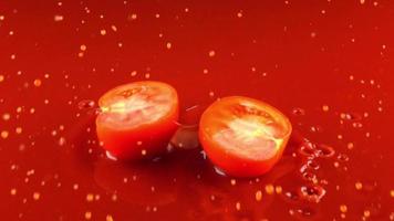 reife geschnittene Tomate, die in rotes Wasser fällt video