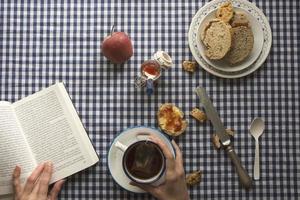 woman having breakfast, his hands and a book photo