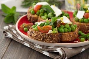 Green peas with cherry tomatoes, feta cheese, mint on toast photo