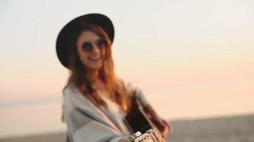 slow motion. beautiful girl playing the guitar in a wheat field