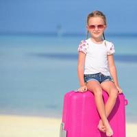 niña sentada en el equipaje rosa foto