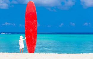 Girl standing with a red surfboard photo