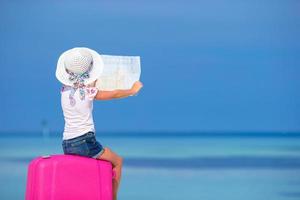 niña sosteniendo un mapa en la playa foto