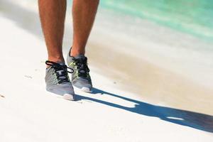 Close-up de los zapatos de un corredor en la playa. foto