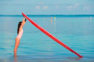 mujer con tabla de surf roja en el agua foto