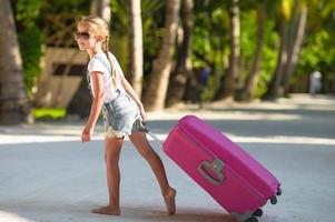 Girl pulling luggage behind her photo