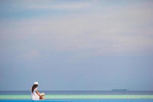 Woman sitting by an infinity pool while reading photo