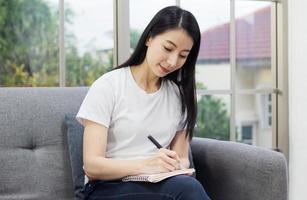 mujer escribiendo en un diario en el sofá foto