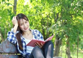 mujer asiática leyendo un libro en el parque foto