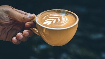 Hand holding a latte in a yellow mug photo