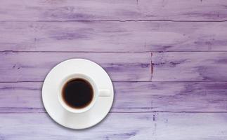 Vista superior de la taza de café sobre un fondo de madera púrpura foto