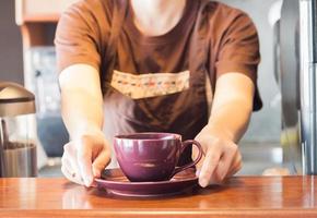 Barista offering purple cup of coffee photo