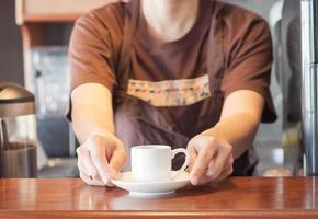 Barista offering mini white cup of coffee photo