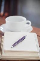 bolígrafo morado en un cuaderno con una taza de café foto