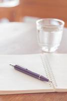 Notebook and pen with a glass of water