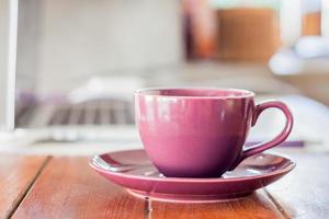 taza de café púrpura en una estación de trabajo foto