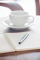 Cuaderno en blanco con bolígrafo sobre una mesa de madera foto