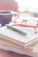 Pen and eyeglasses on a notebook in a coffee shop photo