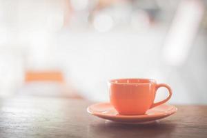 taza de café naranja sobre una mesa foto