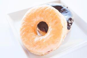 Glazed and chocolate donuts on a white plate photo