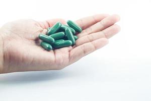 Hand holding green pills photo