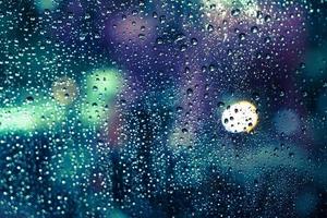 Rain drops on the window with colorful bokeh photo