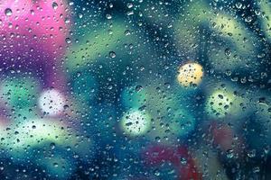 Rain drops on the window with colorful bokeh photo