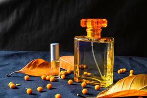 frasco de perfume dorado y hojas de naranja