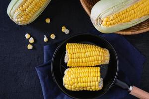 Raw fresh corn in pan on black background