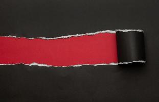 Black torn paper on red background photo