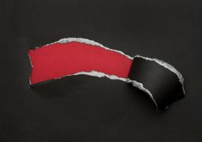 Black torn paper on red background photo