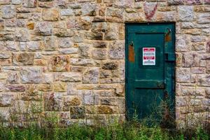 Green metal door in the stone wall photo