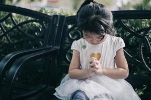 Three year old girl prays to god at park outdoors photo