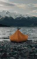 Orange kayak on gray sand near body of water during daytime photo