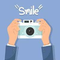 Hands holding a retro camera with the word smile vector