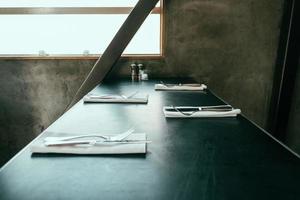 Black table with sets of silverware photo