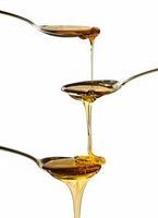 Honey falling on metal spoons with a white background photo