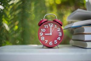 Red alarm clock with book on nature garden background photo