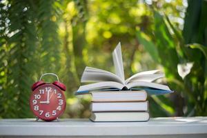 Red alarm clock with book on nature garden background photo