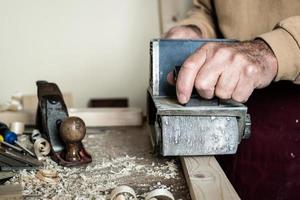 Carpenter doing workpiece processing on light brown wooden table photo