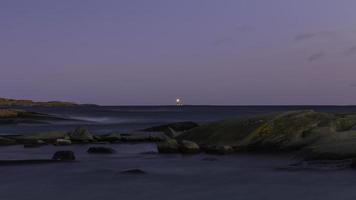 Body of water with distant lighthouse photo