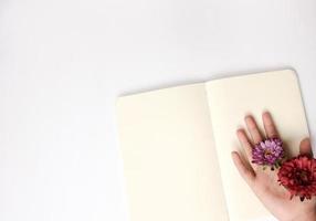 Hand holding flowers on a blank notebook photo