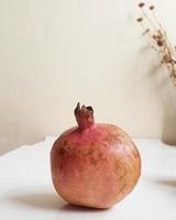 Pink pomegranate on a white table photo