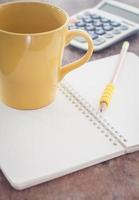 Yellow mug and pencil on a notebook photo