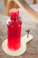 Red juice bottle on a wooden tray photo