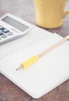 lápiz amarillo y calculadora en un bloc de notas foto