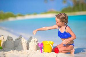 niña construyendo un castillo de arena foto