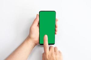 Mujer sosteniendo un teléfono móvil de pantalla verde con un fondo blanco. foto